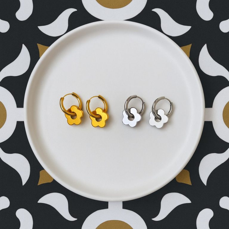 Boucles d'oreilles en forme de fleur, une paire dorée et une paire argentée sur assiette.