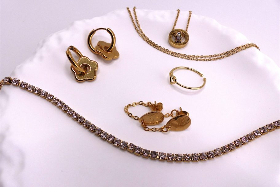 Bijoux en or comprenant boucles d'oreilles, chaînes et une bague sur un plateau.