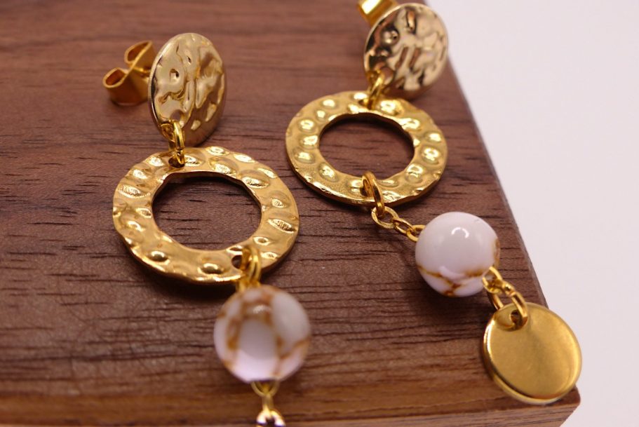 Boucles d'oreilles dorées avec des cercles et des perles blanches marbrées.